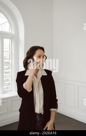 Mixed race woman in business casual attire talks on mobile phone Stock Photo