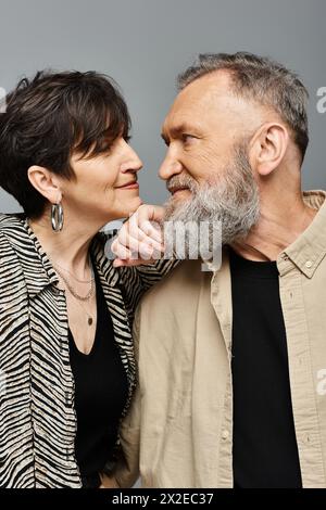 A middle-aged man and woman stand side by side in stylish attire, exuding sophistication and grace in a studio setting. Stock Photo