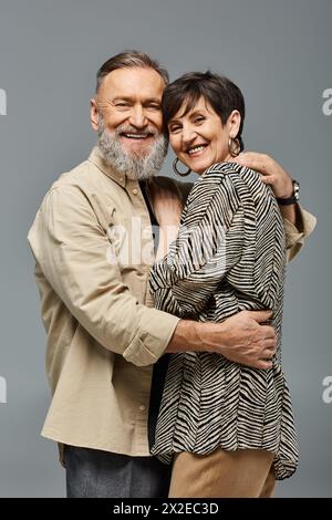 A middle aged couple in stylish attire sharing a warm, heartfelt hug in a studio setting, showing love and connection. Stock Photo