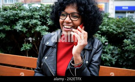 African American middle aged woman with curly hair talking on mobile phone in a city Stock Photo