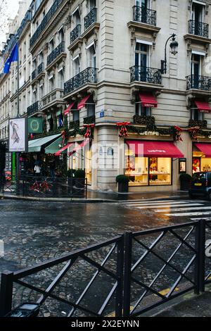 Rainy day on a bustling Paris street corner with shops. Stock Photo