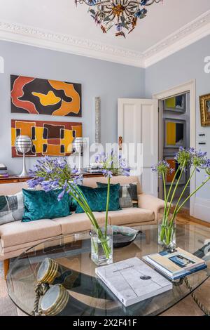 Modern artwork above beige sofa with cut flowers on coffee table in Georgian townhouse. Paultons Square, Chelsea, London, UK. Stock Photo