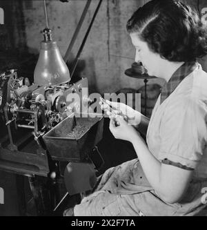 STEN GUN PRODUCTION IN BRITAIN, 1943 - An important part in the production of breech blocks for Sten guns is the spring. Here Jessie Hemingway tests every spring produced for pressure at a spring factory in the Midlands. If any of the springs are too weak or too strong, they are discarded Stock Photo