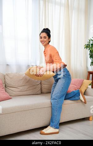 A stylish woman sitting comfortably on a couch, gently holding a pillow. Stock Photo