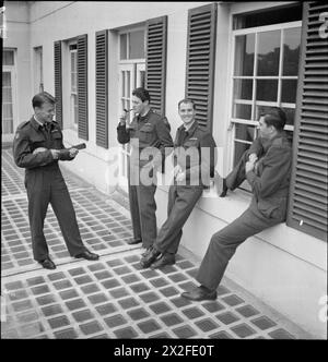 AMERICANS IN BRITAIN: THE WORK OF NO 121 (EAGLE) SQUADRON RAF, ROCHFORD, ESSEX, AUGUST 1942 - Flying Officer Osbourne plays a tune on his banjulele as entertainment for his Eagle Squadron colleagues on the terrace of the old English house in which they are billeted. Left to right, the 'audience' is: Pilot Officer Kearney (smoking a pipe), Pilot Officer Slater and Pilot Officer Padget (seated on the window sill) Stock Photo
