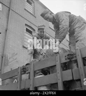 BRITISH GOODS IN US MARSHALLING YARDS: ANGLO-AMERICAN CO-OPERATION IN WARTIME BRITAIN, 1943 - Pfc Walter Toye (left) of 4609 Hedge Street, Philadelphia and Pfc Francis P Owen, of Port Tobago, Maryland, load a bale of cotton waste onto a lorry at a US marshalling yard, somewhere in Britain. The lorry is just about to set off to a neighbouring unit with a week's supply of goods Stock Photo