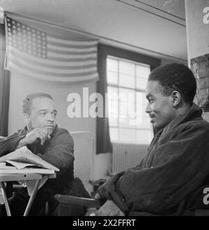 AMERICANS IN BRITAIN, 1942 - 1945 - Black GIs in Britain: Two Black GIs at a United States hospital in Britain. They are pictured with the Stars and Stripes behind them Stock Photo