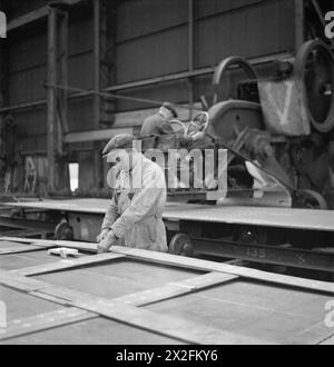 A young man marks rivet holes with a template while another operates a punching machine at Tyneside Shipyards in 1943, photographed by Cecil Beaton. Stock Photo