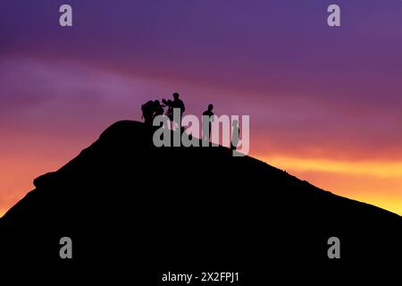 Silhouetted team conducting volcano research during picturesque sunset backdrop Stock Photo