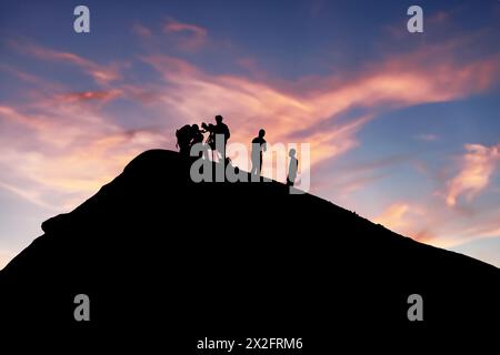 Silhouetted team conducting volcano research during picturesque sunset backdrop Stock Photo