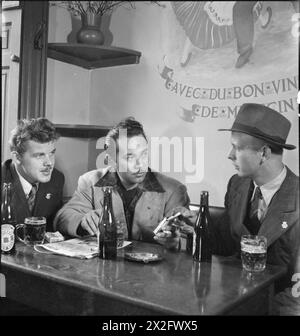 THE SEVEN SEAS CLUB: LIFE AT THE MERCHANT NAVY CLUB, EDINBURGH, SCOTLAND, 1943 - Werner Petersen (left) and Hans Christensen (right) from Denmark join Charles Andrade, an American Merchant Seamen from Honolulu, for a drink and a smoke in the bar of the Seven Seas Club in Edinburgh Stock Photo