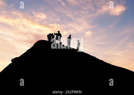 Silhouetted team conducting volcano research during picturesque sunset backdrop Stock Photo