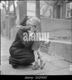 VAN GIRL: HORSE AND CART DELIVERIES FOR THE LONDON, MIDLAND AND SCOTTISH RAILWAY, LONDON, ENGLAND, 1943 - At the end of a busy day delivering goods for the LMS Railway Company, Lilian Carpenter arrives home to be greeted by her son Clarence. He is named after his father, who is in the Army and has not yet seen his son Stock Photo