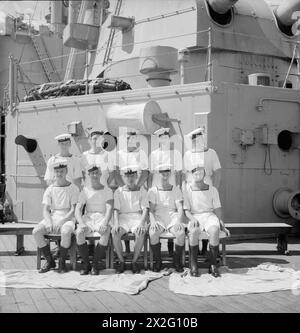 MEN OF THE HMS SUFFOLK, A CRUISER SERVING WITH ADMIRAL JAMES SOMERVILLE'S EASTERN FLEET. 12 DECEMBER 1943, TRINCOMALEE. THE MEN ARE DIVIDED INTO GROUPS BY TOWN AND/OR DISTRICT. - Walthamstow group. Front row, left to right: AB C Dennett; L/Stoker A Mahoney; L/Stoker H Fidler; Stoker A Dean; AB H Griffen. Second row, left to right: AB A Newall, DSM, Sig B Pearce; PO R Tuck; Coder F Tomlin; AB G Tweed Stock Photo