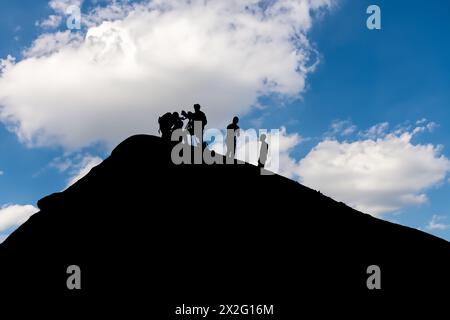 Silhouetted team conducting volcano research during picturesque sunset backdrop Stock Photo