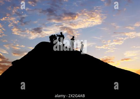 Silhouetted team conducting volcano research during picturesque sunset backdrop Stock Photo