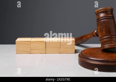 Law. Blank wooden cubes and gavel on light table against gray background Stock Photo
