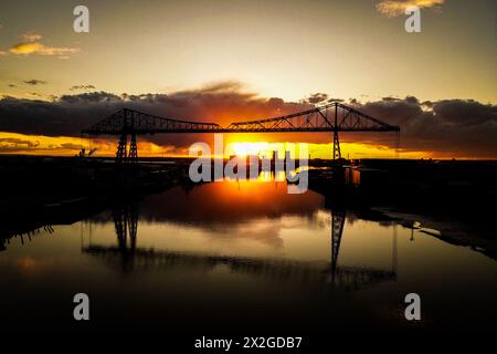 An aerial view of the sun setting over the River Tees behind the Transporter Bridge, in Middlesbrough, North Yorkshire, England on Tuesday 16th April 2024 (Photo: Michael Driver | MI News) Stock Photo