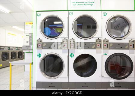 number of white and gray washing machines in empty public laundry Stock Photo