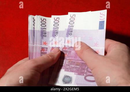 Close-up of many bundle of 500 Euro bank notes in man's hands, red leather, consider Stock Photo