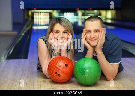 Woman and man lie on parquet alongside and lean chin on hands Stock Photo