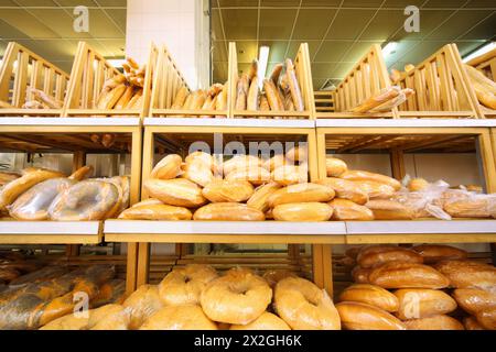 lots of fresh crisp loaves of bread on shelves in store; abundance of delicious soft bread Stock Photo