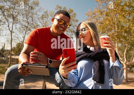 Happy interracial couple checking cell phone outdoors. Stock Photo