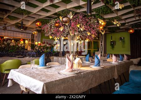 The image shows a beautifully decorated restaurant interior with a floral-adorned ceiling and elegant table settings. Stock Photo