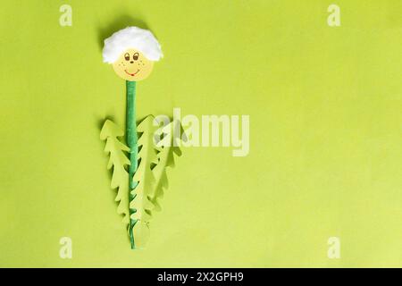 Hand made paper cut dandelion on green cardboard background, spring time concept Stock Photo