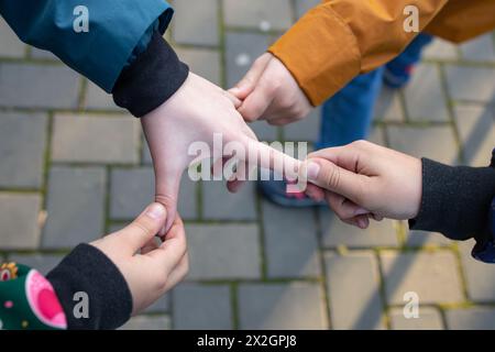 Four child hands pulling fingers, children playing in the park Stock Photo