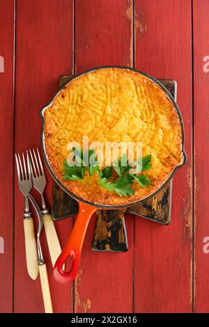 Shepherd's Pie with ground beef, peas, carrots, onions, potato and cheese on old wooden background in cast iron pan. Traditional British dish homemade Stock Photo