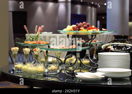 Table with cold snacks and fruits on stand and tableware on luxury stand-up party Stock Photo