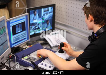 young operator of remote video system controls sound and image at press conference Stock Photo