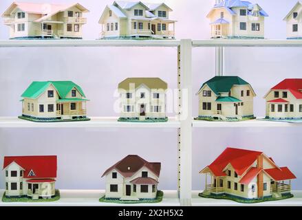 Small different beautiful models of cottages stand on white shelves Stock Photo