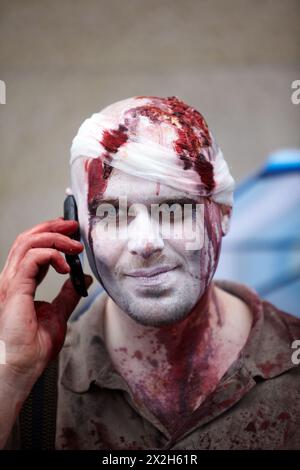 MOSCOW - MAY 14: Unidentified made-up participant with a bandaged bloody head keeps cell phone at his ear at Zombie Parade on Old Arbat, May 14, 2011, Stock Photo