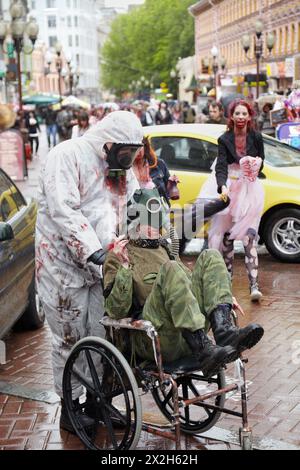 MOSCOW - MAY 14: A pair of unidentified made-up participants in the gas masks at Zombie Parade on Old Arbat, one carries the other in a wheelchair,  M Stock Photo