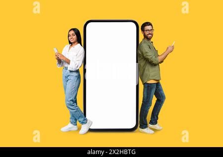 Two Multiracial people using phones next to mockup screen Stock Photo
