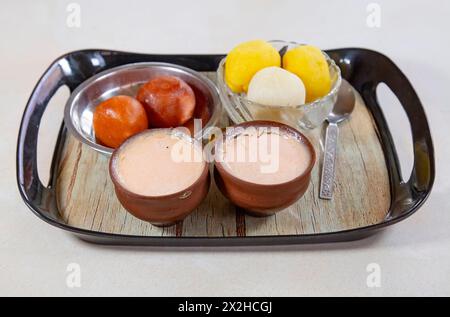 Traditional Bengali desserts on a tray which include sweets like rasgulla, rajbhog, gulab jamun and sweet curd. Stock Photo