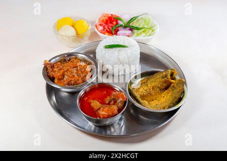 Bengali non vegetarian food 'Thali' comprising of plain rice with chicken, prawn and Parse fish side dishes along with sweets and salad Stock Photo