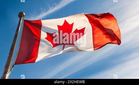 Die Fahne von Kanada flattert im Wind, isoliert gegen blauer Himmel Stock Photo