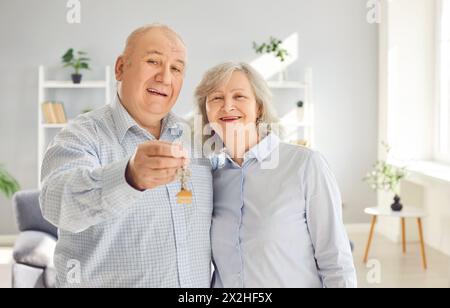 Happy senior couple holding a key in their hands standing in a new apartment on moving day. Stock Photo