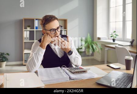 Tired, sleepy and bored financial accountant is sitting at work desk and yawning Stock Photo