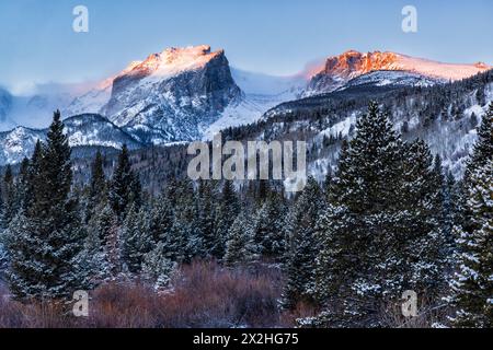 The first golden light of day hit Hallett Peak and Flattop Mountain with fresh snow on the trees, seen from the Storm Pass trailhead, Rocky Mountain N Stock Photo