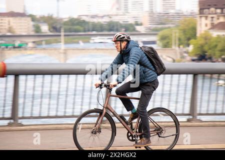 Basel, Switzerland - April 18, 2024: Mature cyclist riding bicycle on Wettstein bridge Stock Photo