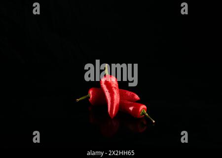 Group of fresh red chili peppers on a black surface. Stock Photo