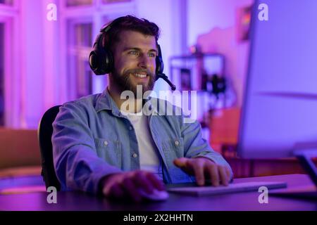 Bearded man using a headset at the computer Stock Photo