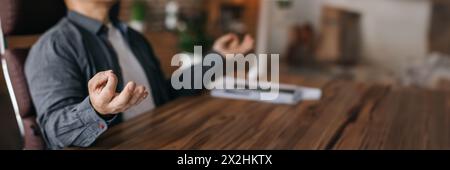 Man resting in chair at table with laptop in office Stock Photo