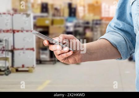 Warehouse factory contact holding mobile cell phone. Man hand holding cell phone checking factory warehouse management, person smart logistic mobile i Stock Photo