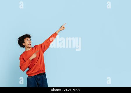 Joyful black guy pointing upwards on blue background Stock Photo