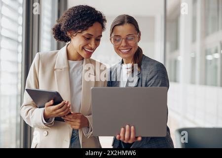 Young female freelancers standing in coworking while working on project and use gadgets Stock Photo
